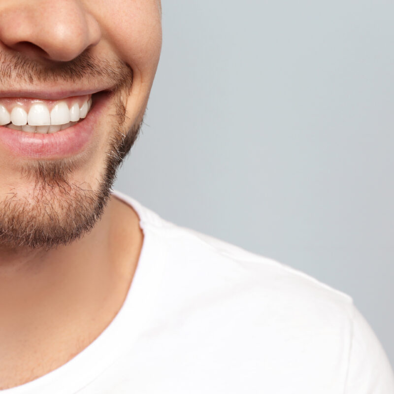 Young,Man,With,Beautiful,Smile,On,Grey,Background.,Teeth,Whitening